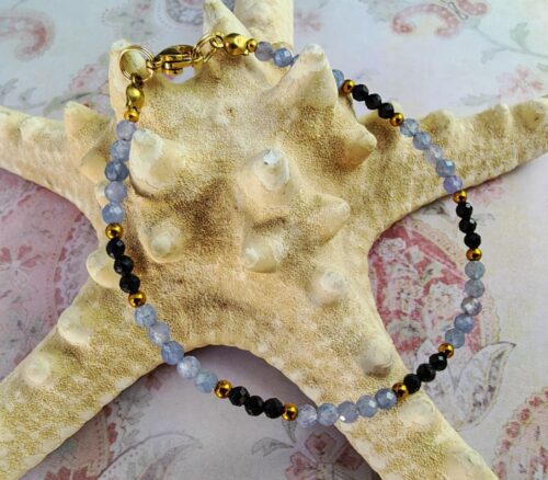 bransoletka na żyłce jubilerskiej z fasetowanymi koralikami z tanzanitu i czarnego turmalinu z przekładkami ze złotego hematytu, zapięcie ze stali nierdzewnej w złotym kolorze